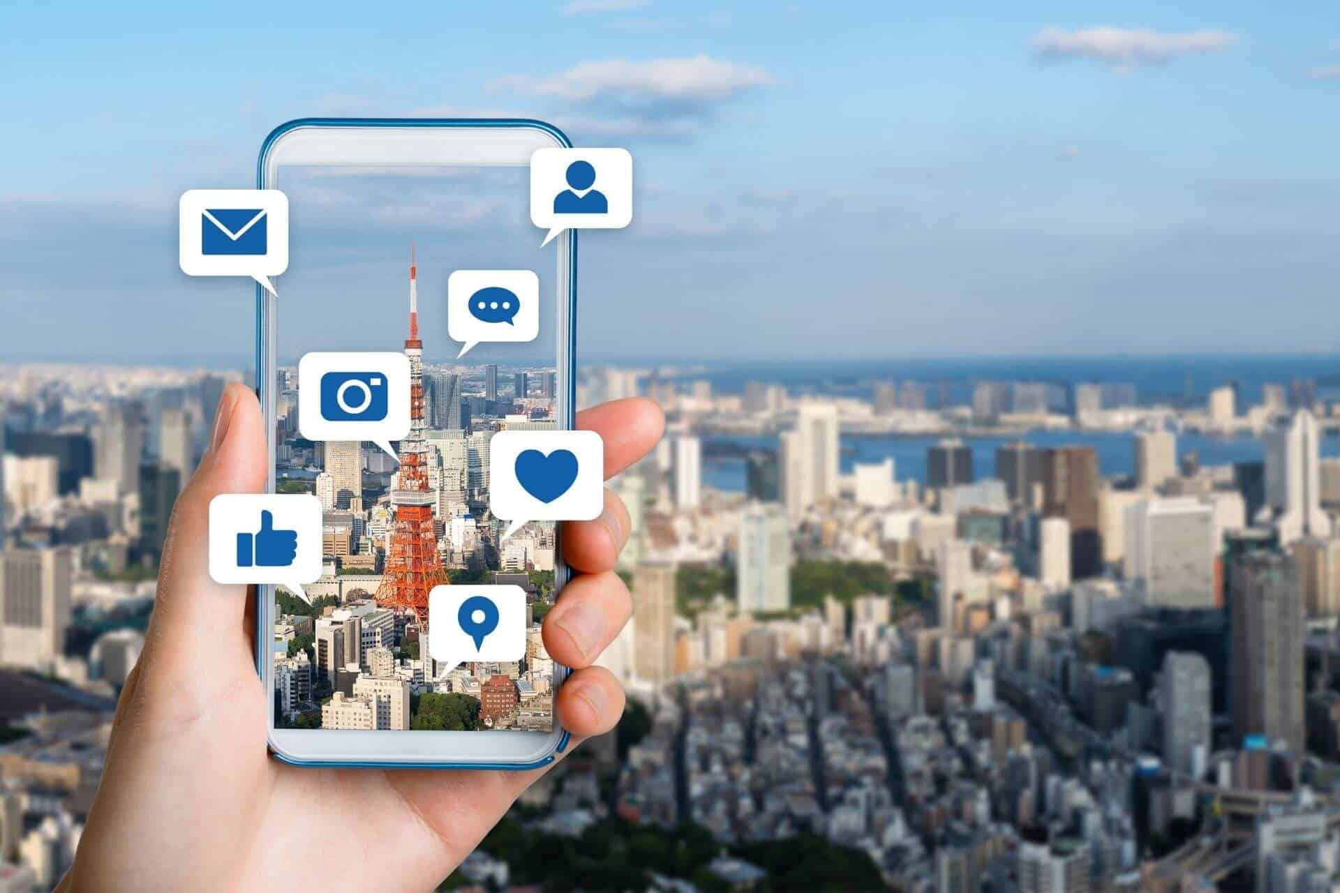 A mobile phone displaying social media icons against a cityscape 