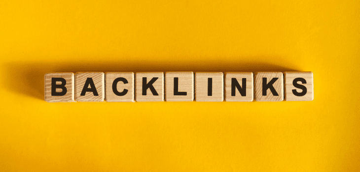 Wooden blocks on a yellow background displaying the word “backlinks”