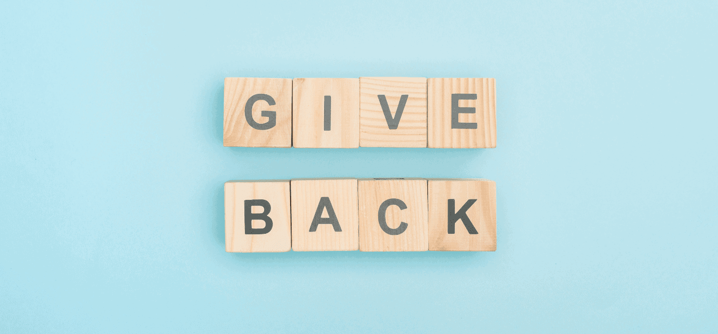 A blue background with “Give Back” written on wooden blocks