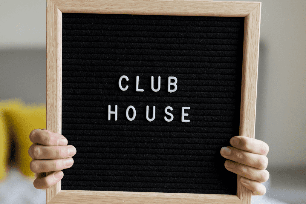 A person holding a black letter board with the words “club” and “house” spelled out on it.