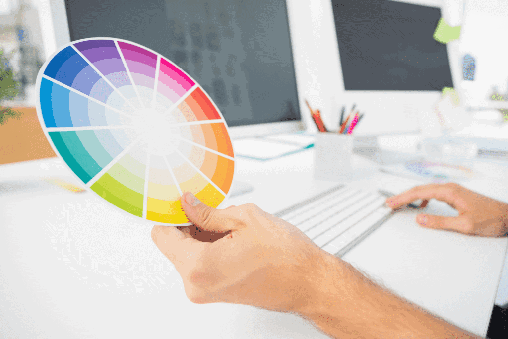 a hand holding a colour wheel in front of a computer 
