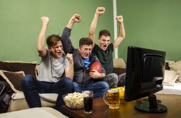 Friends cheering watching the Superbowl game on television.