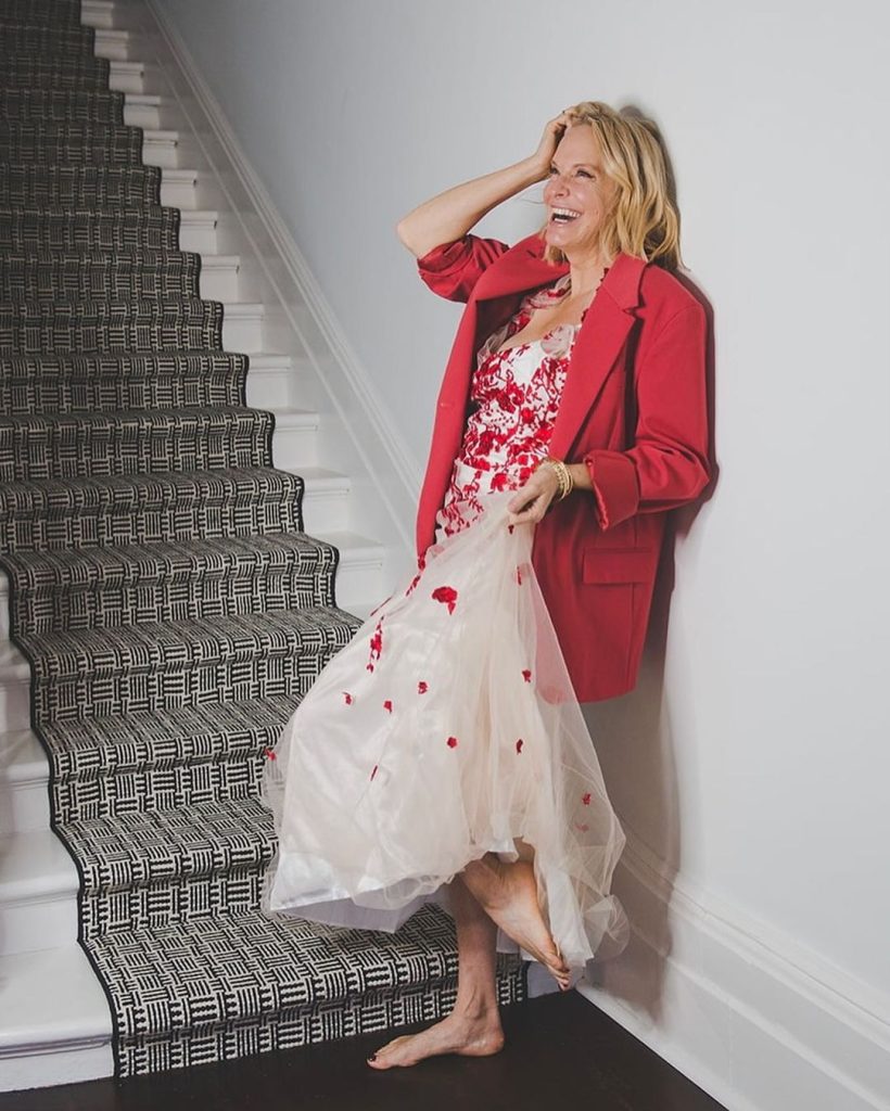 Julia Grieve on a staircase wearing a floor length dree and red blazer