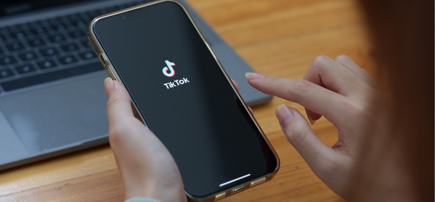A hand holding a phone with a TikTok logo displayed on the screen