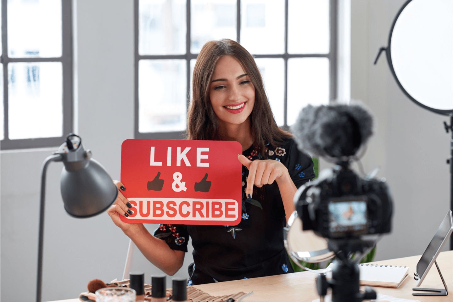 an influencer posing with a sign that says ‘like and subscribe’