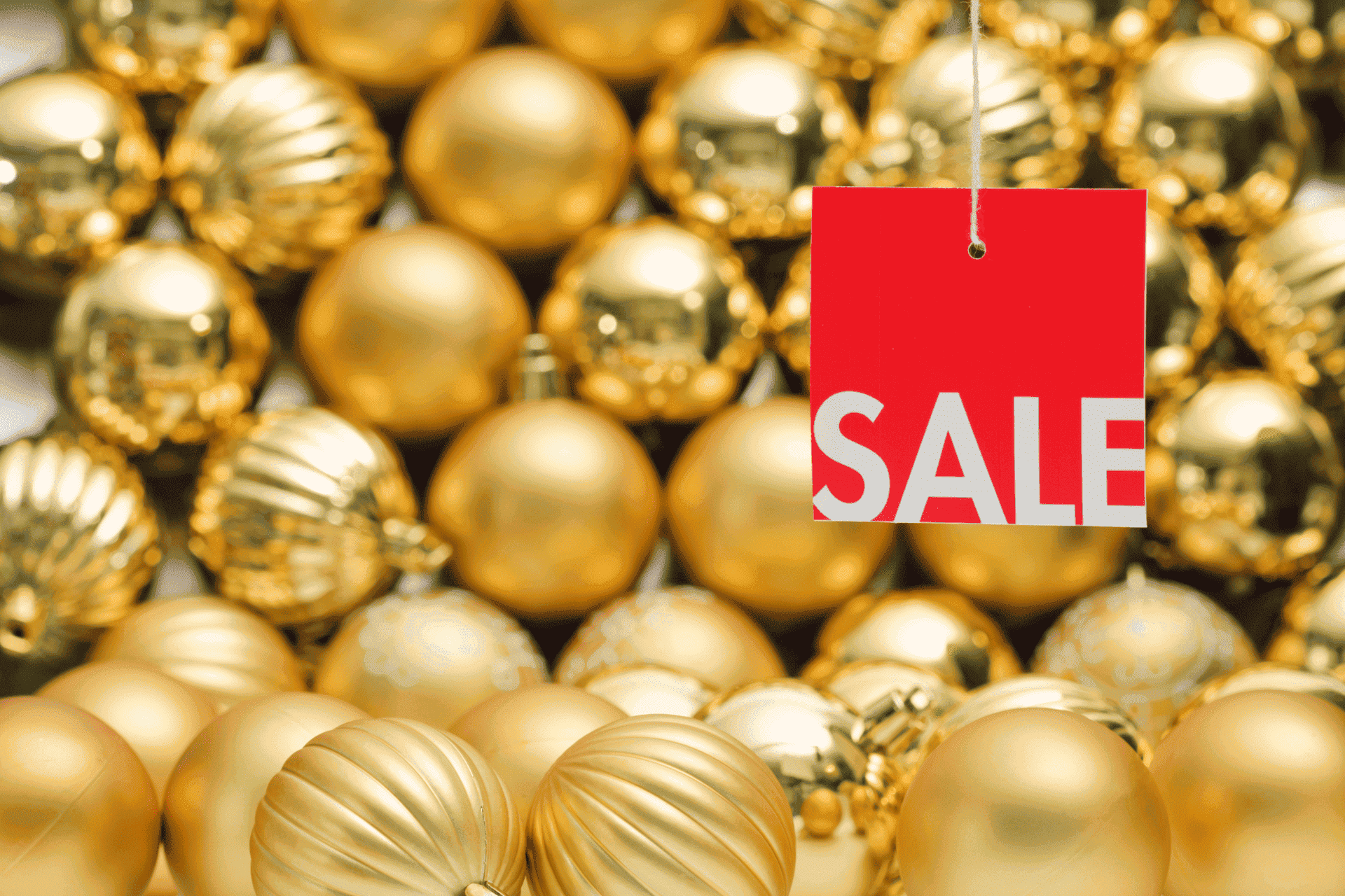 a red sale tag hanging in front of gold ornaments